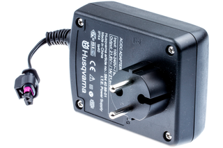 Vedere de sus a unui adaptor de curent alternativ Husqvarna cu mufă și conector vizibile.
