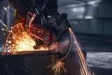 A construction worker using a power cutter, generating sparks while cutting through a concrete block.
