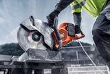 A construction worker using a power cutter to cut concrete blocks on a construction site.