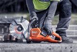 A construction worker using a power cutter on a concrete surface.