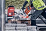Construction worker using a power cutter on concrete blocks at a construction site.