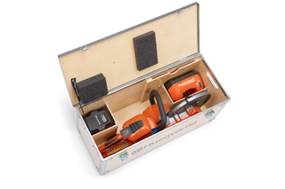 Top view of a Husqvarna chainsaw neatly packed in a wooden box with compartments.