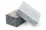 Two stone blocks, one with a speckled texture and the other smooth, positioned on a white surface.