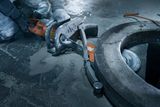 Construction worker using a power cutter on a concrete surface.