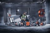 A worker in a construction setting surrounded by various Husqvarna construction tools.