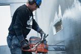 Construction worker using a power cutter on a concrete wall.