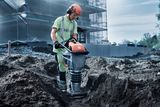 Bouwvakker die een grondverdichter op een bouwplaats bedient.