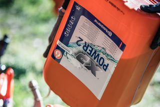 Närbild av en bränslebehållare märkt "Power 2" på en gräsbevuxen yta.