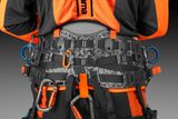 Close-up of a Husqvarna climbing harness with multiple carabiners and attachment points.