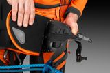 A person adjusting a protective harness with a climbing rope visible.