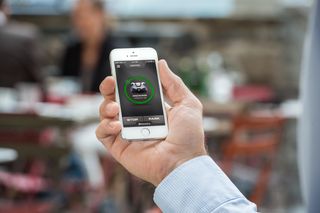 A person holding a smartphone displaying a robotic lawn mower control app.