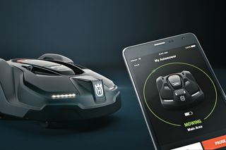 Un robot tondeuse Husqvarna à côté d’un smartphone affichant l’interface de son application de contrôle.