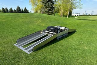 Et plenpleieprodukt på en gresslette med trær og bysilhuett i bakgrunnen.