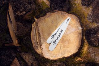 Two Husqvarna chainsaw guide bars placed on a tree stump.