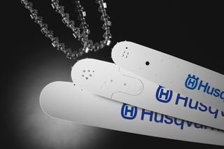 Close-up of Husqvarna chainsaw bars and chain on a dark background.