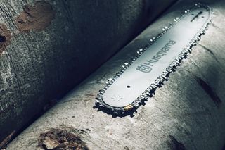 Крупний план шини ланцюгової пилки Husqvarna, що спирається на великі колоди.