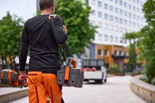 A person carrying two construction products, walking towards a construction site.