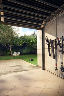 Gardening tools neatly organized on a wall rack in a garage setting.