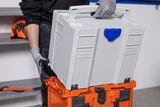 A person stacking Husqvarna toolboxes in a workshop setting.