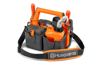 Vista frontal de uma caixa de transporte de baterias Husqvarna com compartimentos para baterias e acessórios.