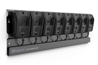 A Husqvarna charging rail with eight battery chargers mounted on it.