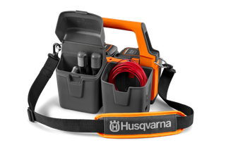 Vista frontal de uma mala de transporte Husqvarna com compartimentos para acessórios, incluindo cabos e garrafas.