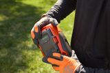 A person holding a Husqvarna battery, showcasing the battery's charge level indicator.