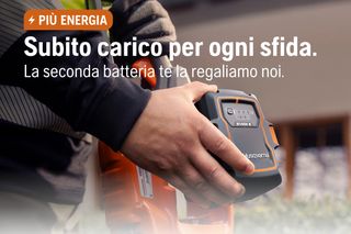 Primo piano di una persona che inserisce una batteria Husqvarna in un utensile. Il testo italiano offre una seconda batteria.