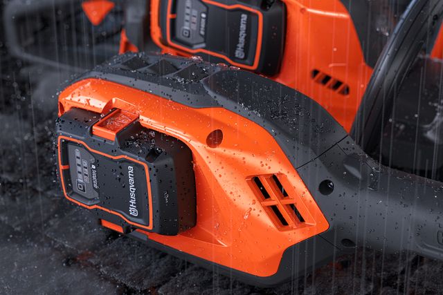 Nahaufnahme des Husqvarna-Batteriefachs auf nasser Oberfläche.
