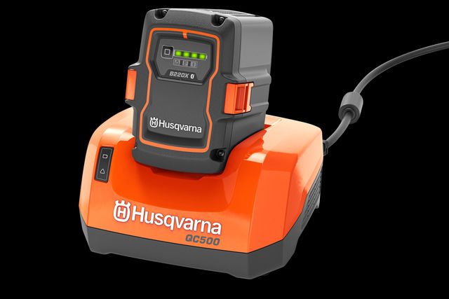 Vue de face d’un chargeur de batterie Husqvarna QC500 avec une batterie fixée.
