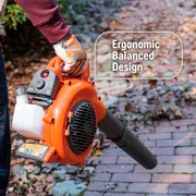 A person holding a leaf blower with an ergonomic balanced design, standing on a brick path with fallen leaves.