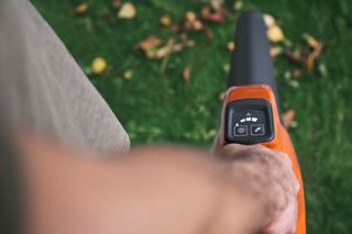 Una persona que usa un soplador de hojas para limpiar hojas caídas en una plataforma de madera.