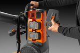 Operator adding a battery to a Husqvarna backpack blower.