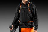 A person with a leaf blower, wearing a harness and work gear.