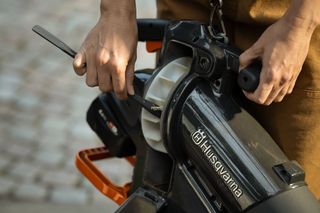 Osoba držiaca vysávač Husqvarna a predvádza, ako používať čistý poklop.