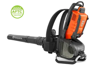Side view of a Husqvarna backpack leaf blower in a studio, with a certification badge.