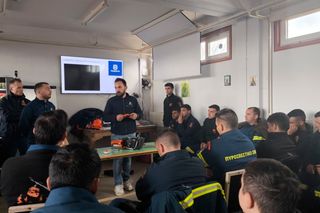 Μια ομάδα ατόμων που παρακολουθούν μια εκπαιδευτική συνεδρία σε εσωτερικούς χώρους, με έμφαση σε ένα προϊόν Husqvarna.