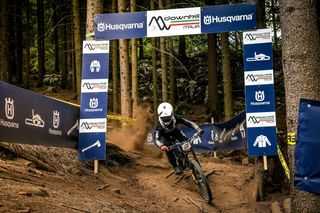 Un ciclista in discesa su una pista forestale durante un evento sponsorizzato da Husqvarna.
