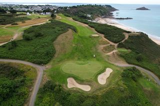Vue aérienne d’un terrain de golf côtier avec des bunkers de sable et une végétation luxuriante.