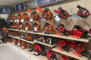 壁面の棚に複数のチェンソーをディスプレイし、ハスクバーナやゼノアの看板を見えるように配置。