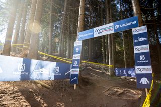 Ingresso a un sentiero forestale contrassegnato con il marchio Husqvarna, circondato da alberi.