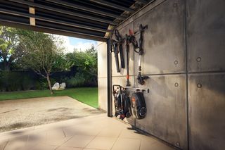 Gartengeräte ordentlich organisiert auf einem Wandregal in einer Garagenumgebung.