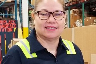 A person wearing work gear in a warehouse setting, with visible shelving and boxes.