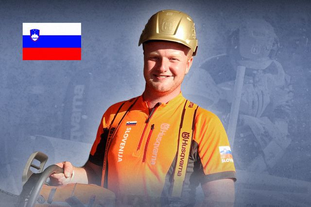 En person som bär en Husqvarna-skyddshjälm och arbetsutrustning och håller en motorsåg med den slovenska flaggan i bakgrunden.