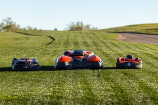 Three robotic lawn mowers positioned on a grassy field, showcasing their design and functionality.