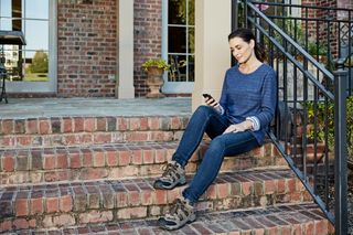 A person sitting on brick steps outside a building, holding a smartphone.