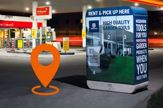 Bir benzin istasyonunda, konum simgesi yer paylaşımlı Husqvarna bahçe aletleri reklamını gösteren dijital bir kiosk.