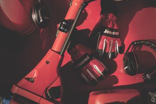 Jonsered branded gloves and headphones placed on a red surface.