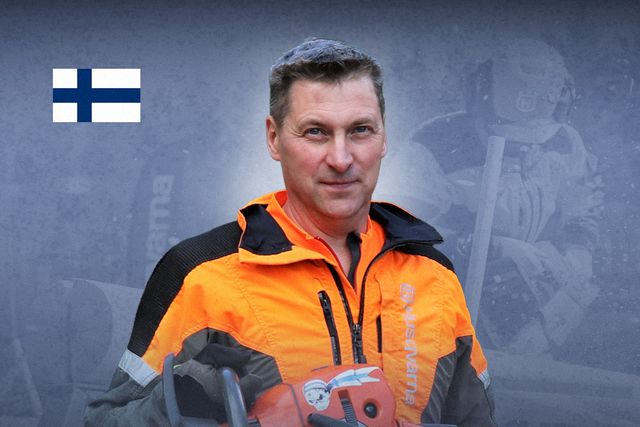 En person i arbetskläder håller i en motorsåg från Husqvarna med en finsk flagga i bakgrunden.