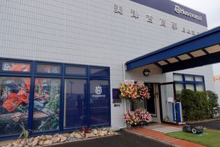 チェーンソーを使用している人物を示すディスプレイウィンドウを備えたハスクバーナ店舗の外観。